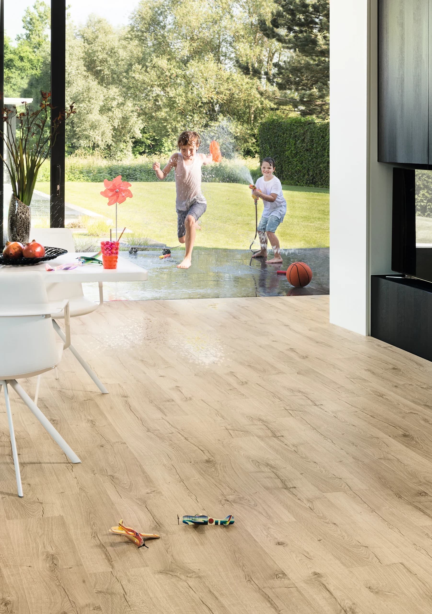 Warme laminaatvloer in een woonkamer met spelende kinderen in de tuin