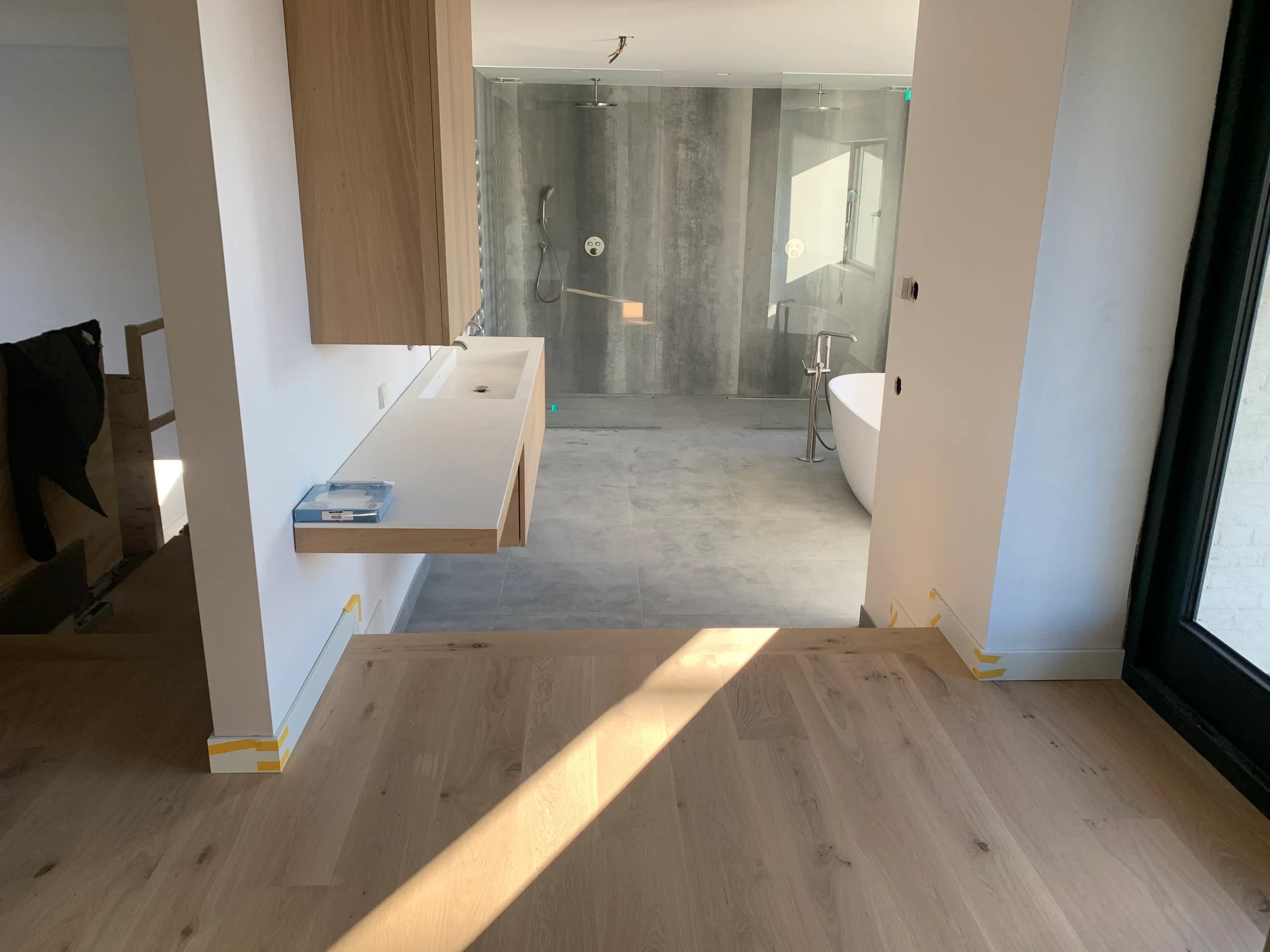 Lichte eiken vloer in de slaapkamer die overloopt naar de open badkamer met vrijstaand bad, Nieuwegein