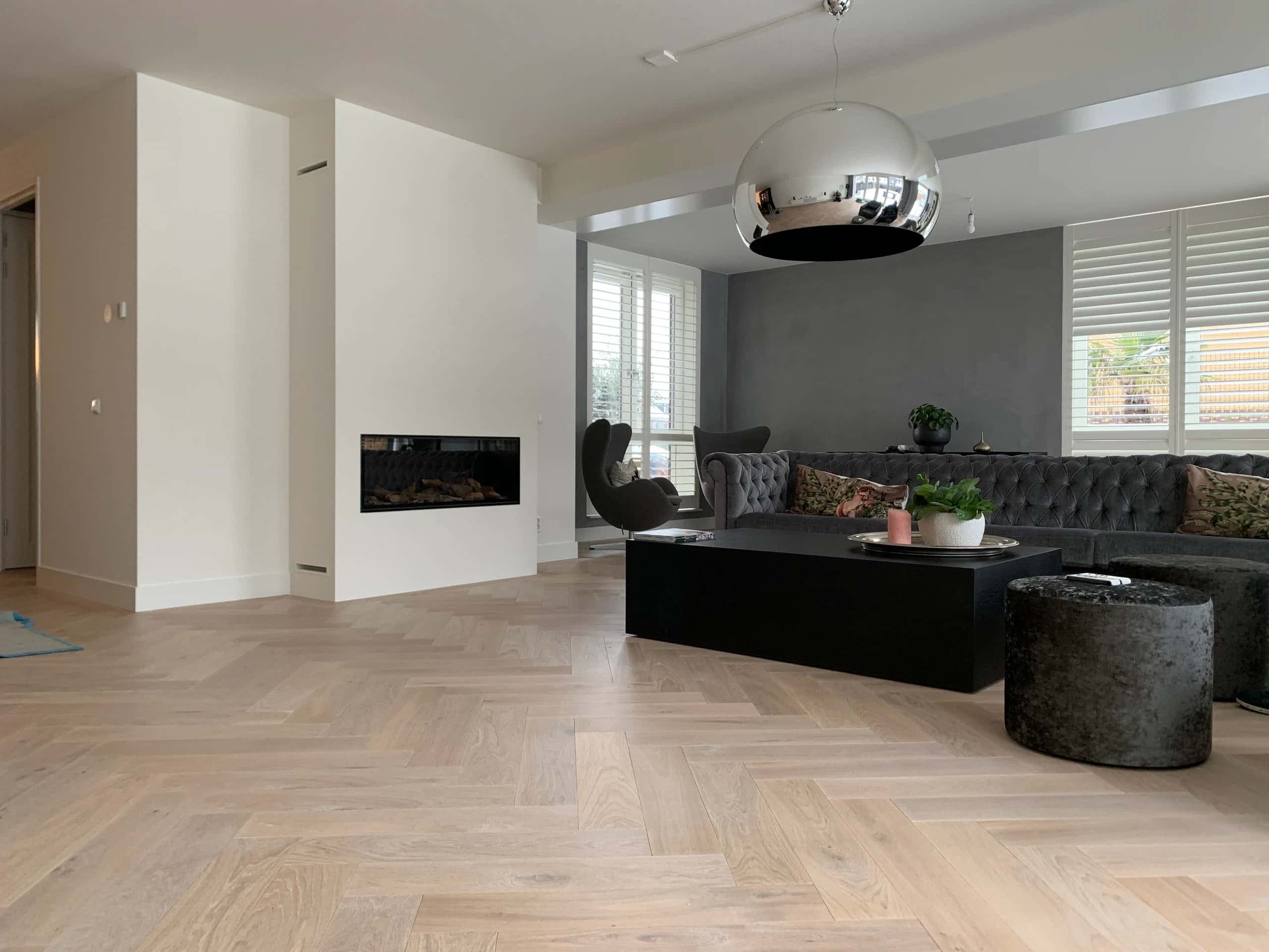 Visgraat lamelparket in een warme woonkamer met haard