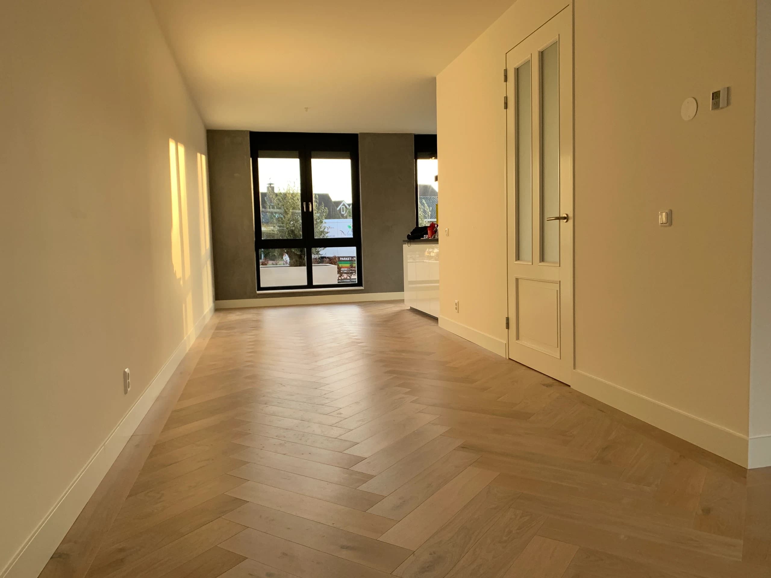 Visgraat lamelparket in warm zonlicht in een lichte kamer, Vianen