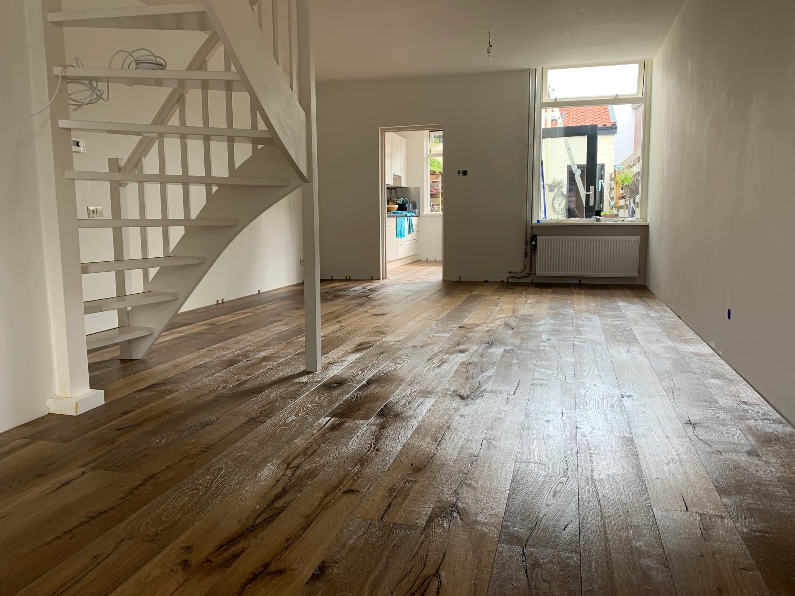 Gerookte eiken planken in een lichte woonkamer met open trap, Zeist