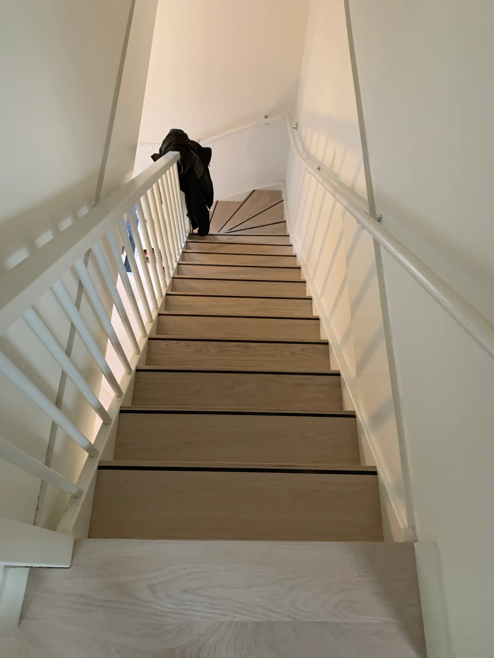 Lichte eiken wenteltrap met witte balustrade, van bovenaf gezien