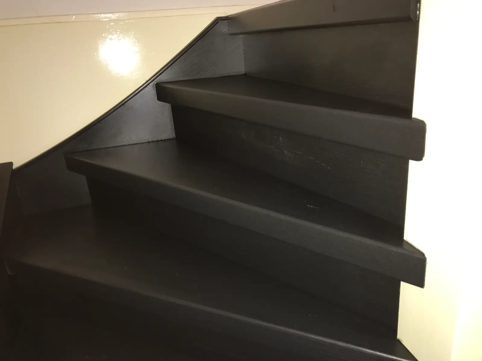 Detail van zwarte laminaat overzettreden met strak zwart stootbord en zijwang