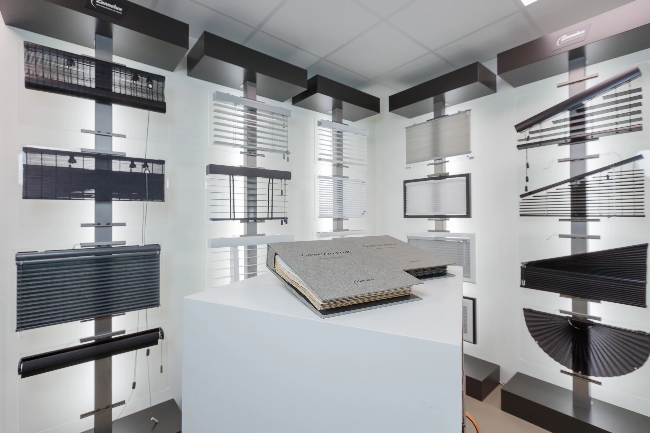 Zonnelux raambekleding-display in de showroom van Deley's Parket: jaloezieën, plissé en geweven hout